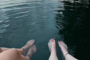 Zwei paar Füße hängen an einem heißen Sommertag zur Abkühlung im erfrischenden See, um das Pitta-Dosha zu senken