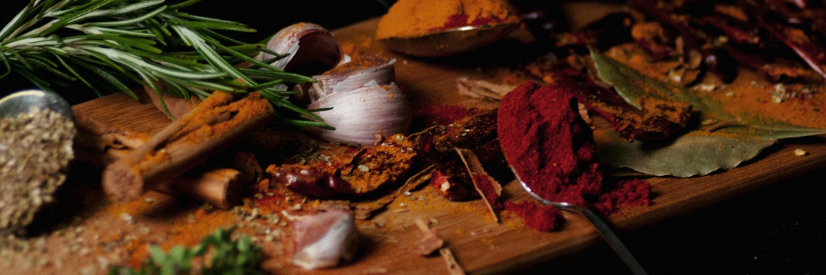 Verschiedene Gewürze auf einem Holzbrett angeordnet, darunter sind auch Gewürze, die laut dem Ayurveda Agni, das Verdauungsfeuer, stärken