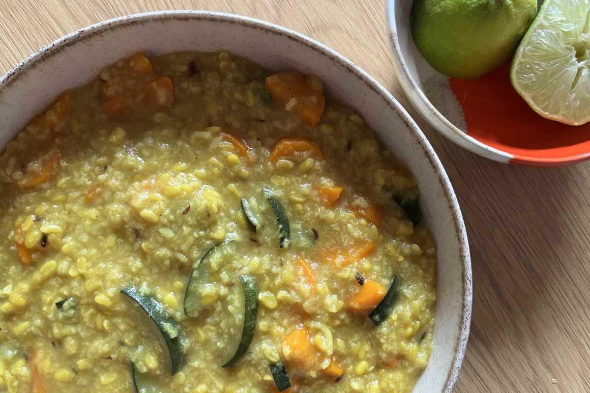 Der ayurvedische Eintopf Kitchari auf einem Teller, daneben eine kleine Schale mit angeschnittener Limette