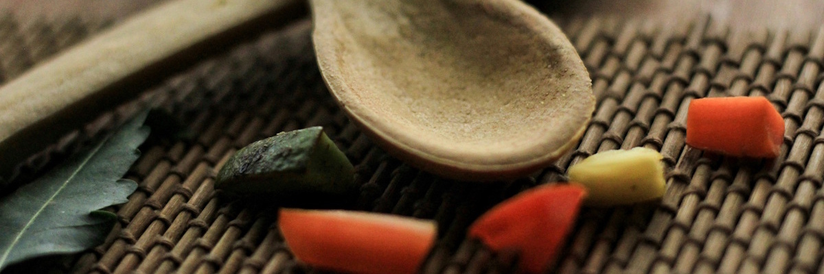 Ein Stillleben mit Holzlöffeln, Kräutern und ayurvedischen Nahrungsmitteln zur Agni Stärkung