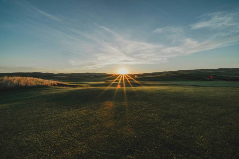 Sonnenuntergang am Horizont hinter einem Feld, der Himmel sanft blau